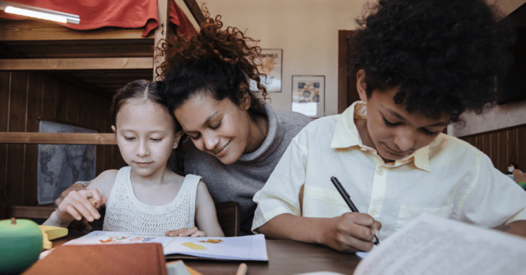 A mother with her two children teaching them from different books.