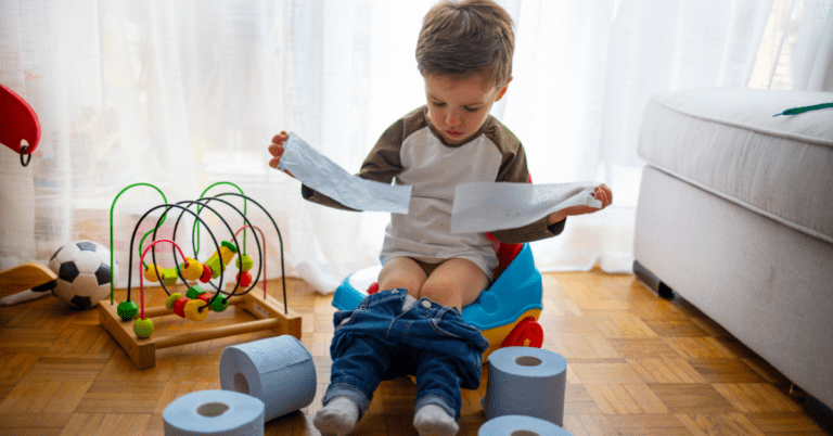 A child potty training on a practice toilet in a living room.