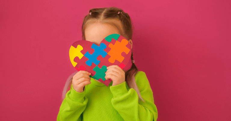 A child hiding their face with a colored heart against a red background